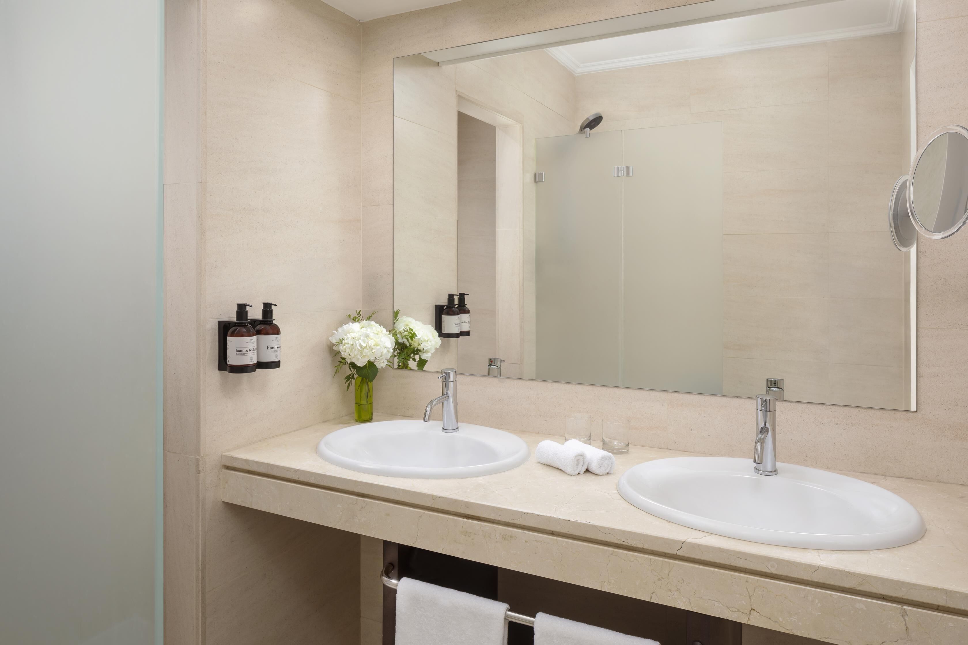 Un baño con dos lavamanos, un espejo grande y un perchero para toallas.