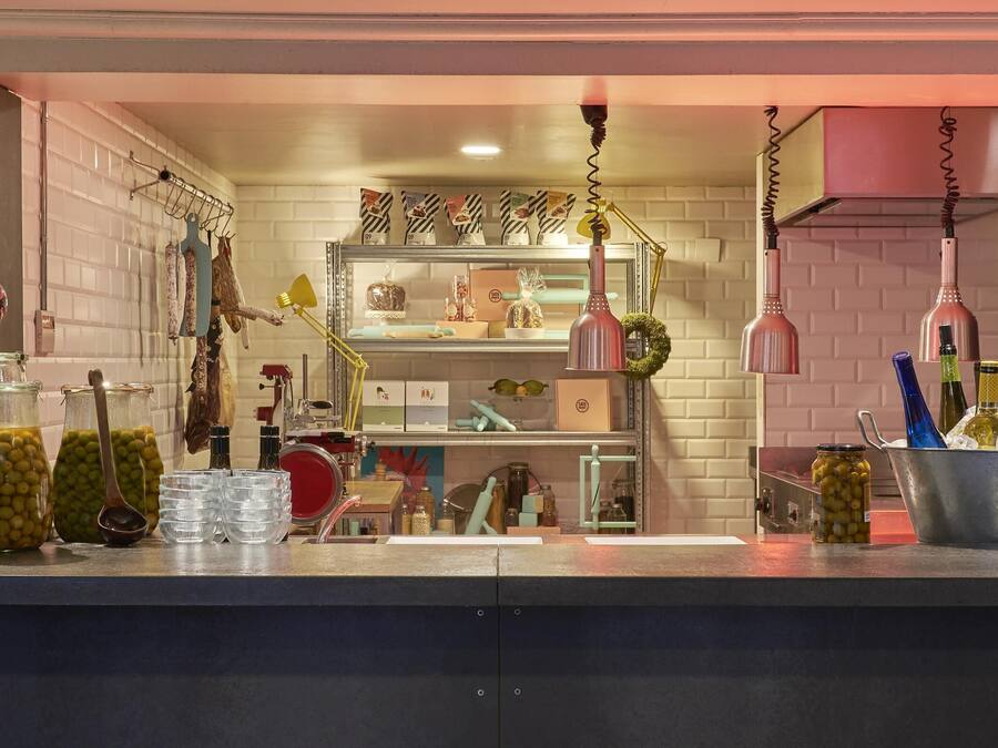 Eine Bar mit Regalen voller Flaschen, Oliven in Gläsern und einem Eimer voller Eis und Flaschen.
