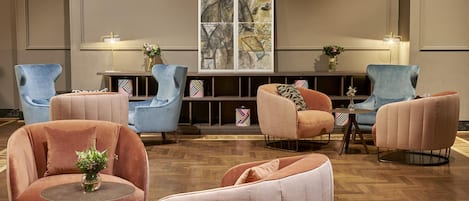 A modern lounge area with plush seating, a central coffee table, and a large abstract artwork on the wall.