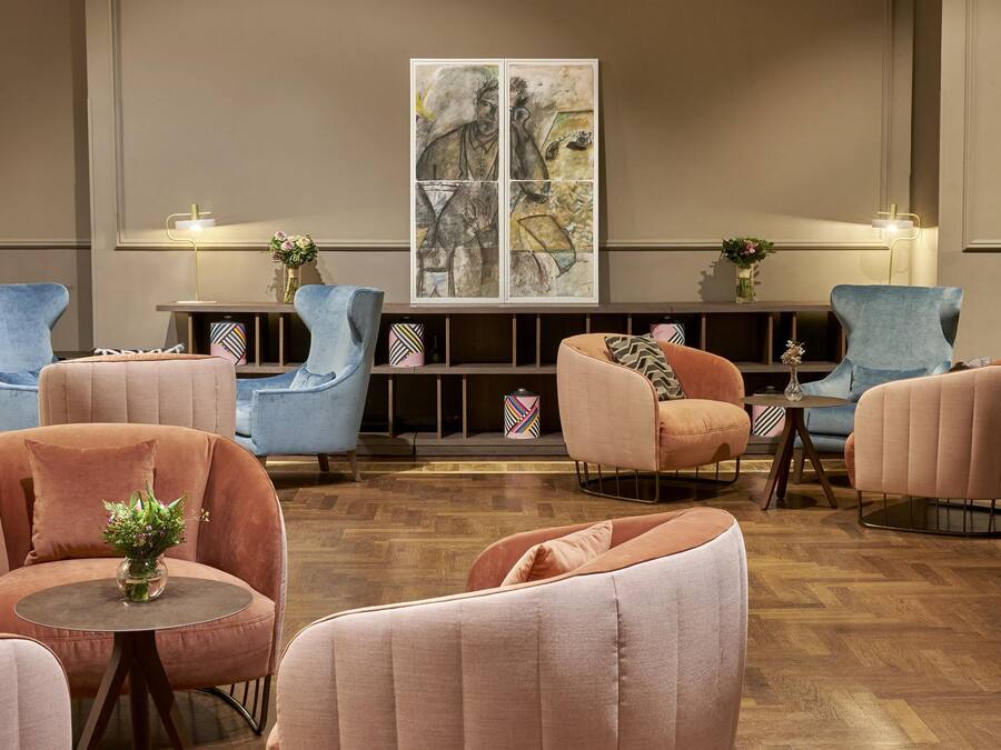 A modern lounge area with plush seating, a central coffee table, and a large abstract artwork on the wall.