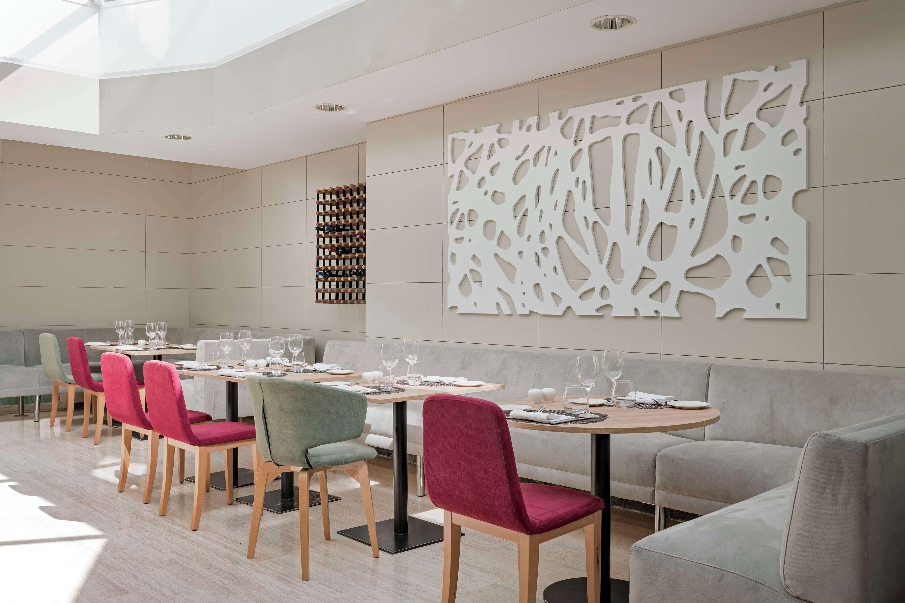 Un comedor moderno con una mesa larga, varias sillas y un panel decorativo en la pared.