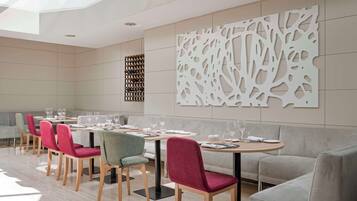 Un comedor moderno con una mesa larga, varias sillas y un panel decorativo en la pared.