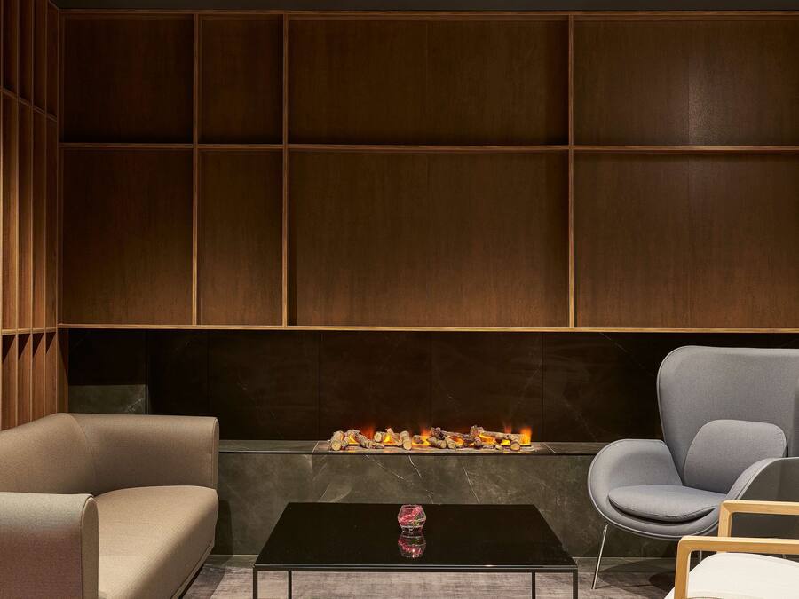 A modern lounge area with a fireplace, leather sofas, and a glass coffee table.