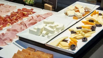 Eine Auswahl an Käse und Wurstwaren auf weißen Tellern angerichtet.