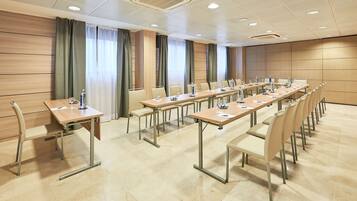 Un salón de conferencias con largas mesas, sillas y un panel de pared de madera.