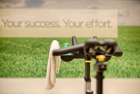 A towel hanging on a bike rack with a motivational sign in the background.