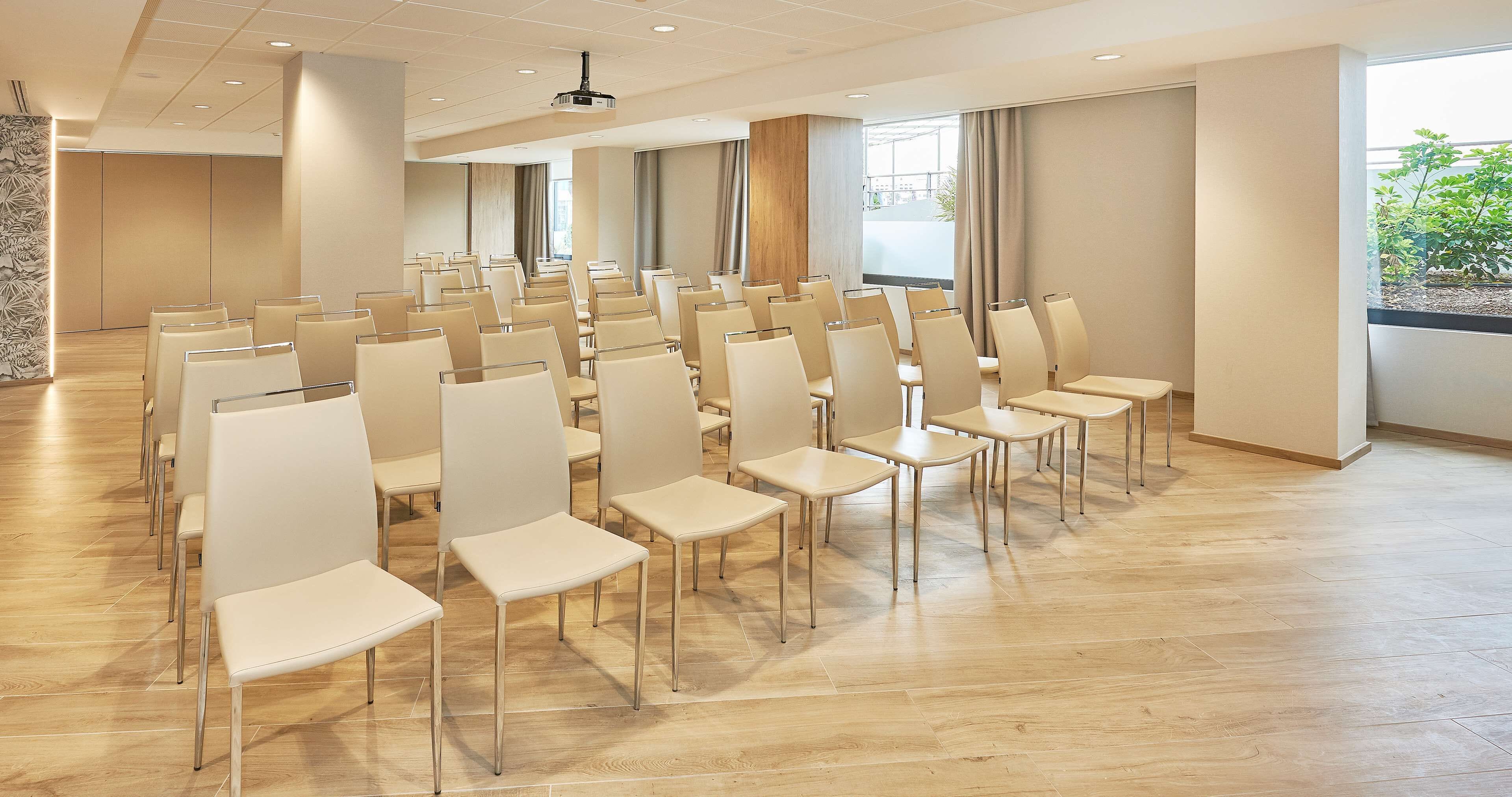 A conference room with rows of chairs and a projector screen.
