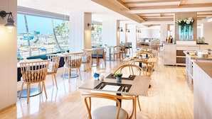 Un restaurante moderno con mobiliario de madera y ventanas amplias con vistas a una zona de piscina.