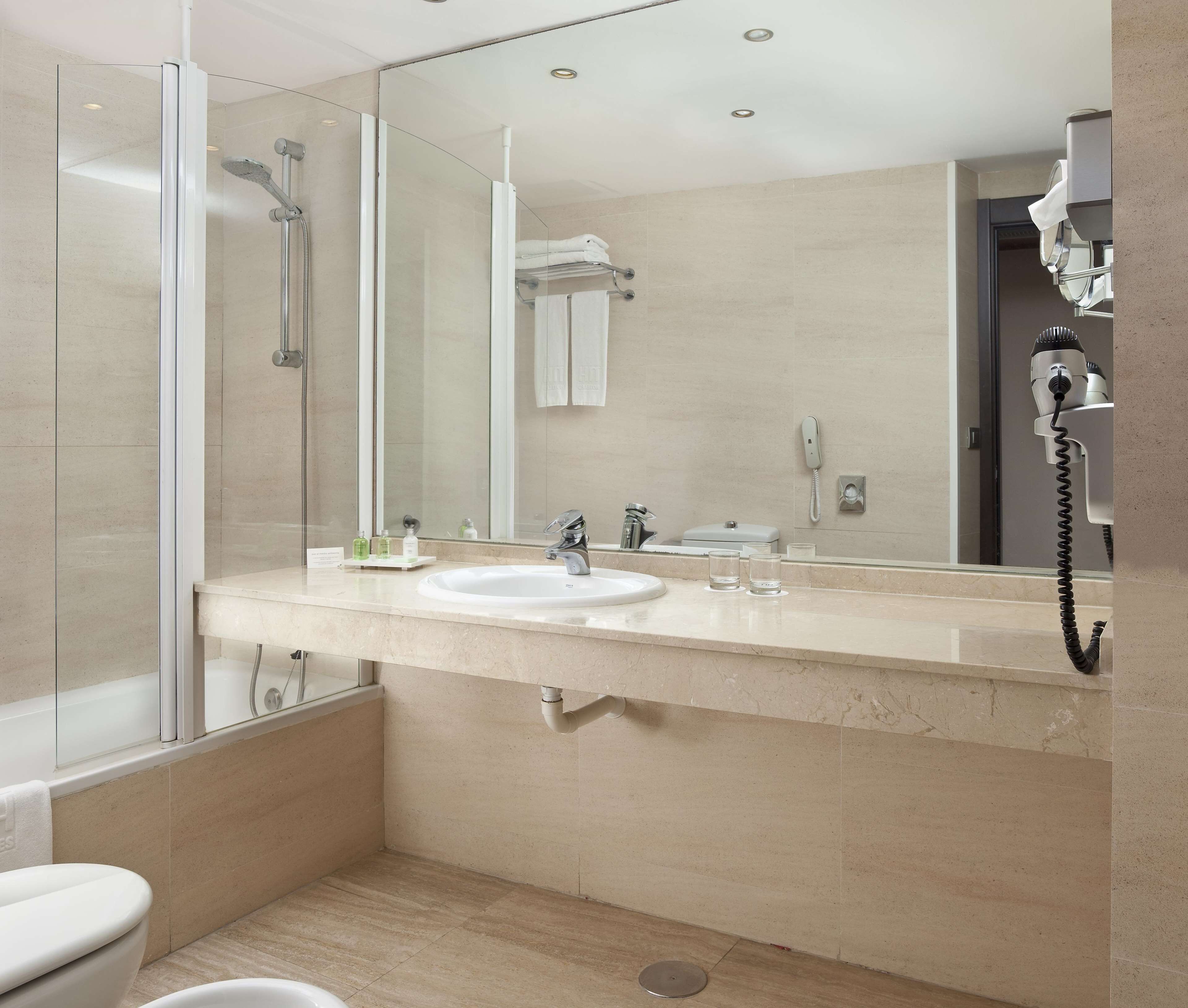 Une salle de bain moderne avec une douche à parois de verre, un lavabo blanc et un grand miroir.