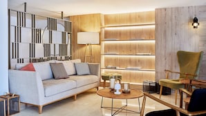 Una sala de estar moderna con un sofá, una mesa redonda de centro, una estantería y una silla.