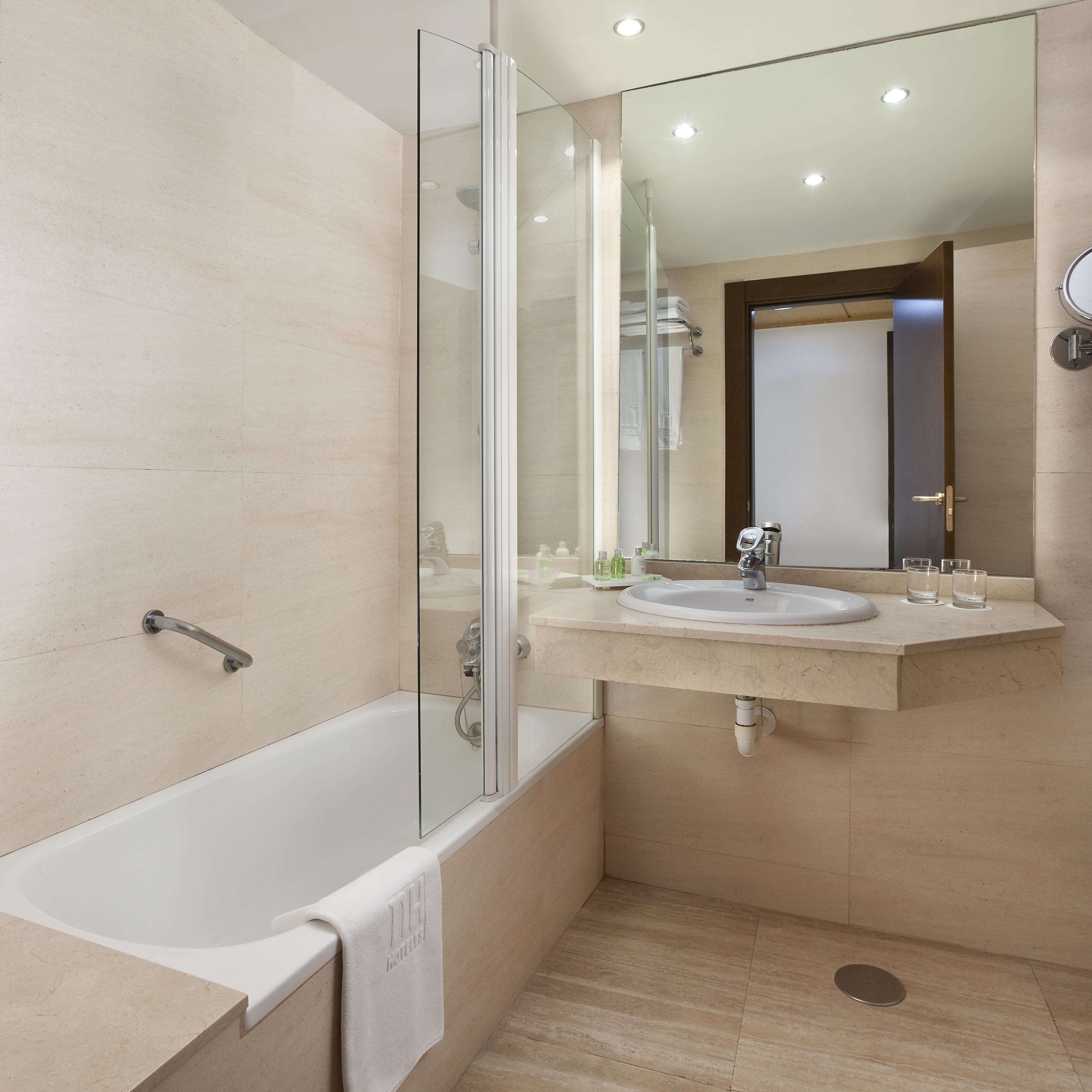 A modern bathroom with a glass-enclosed shower, a bathtub, and a vanity with a sink and mirror.
