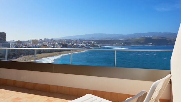 Un balcón con vista al océano y al paisaje urbano.