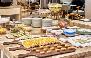 A buffet setup with various food items and serving utensils. - NH Imperial Playa (Las Palmas de Gran Canaria)