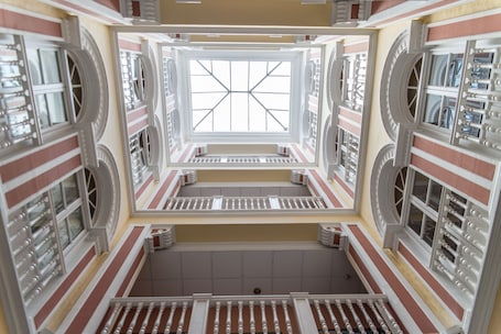 A multi-level atrium with a central skylight, multiple staircases, and a symmetrical design.