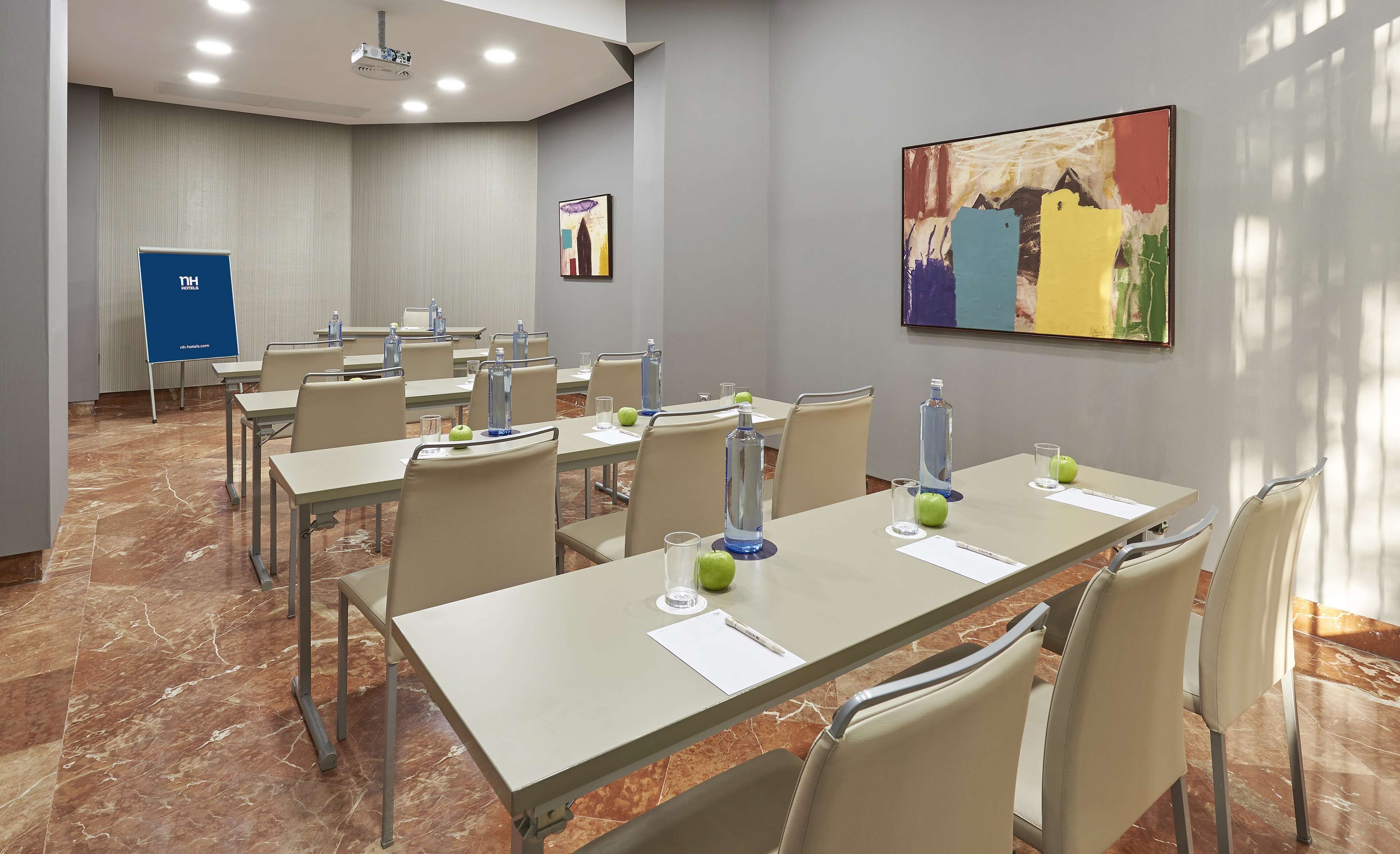 A conference room with multiple tables, chairs, and a projector screen.