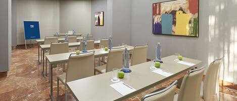A conference room with multiple tables, chairs, and a projector screen.