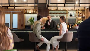 Un espace bar avec un comptoir, des sièges et une variété de bouteilles et de verres exposés sur des étagères.
