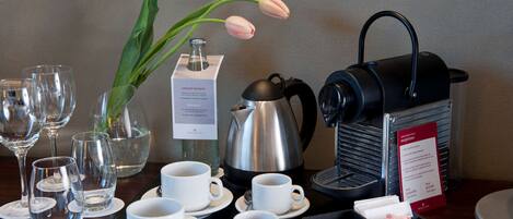 A table with coffee-making equipment, cups, and a flower arrangement.