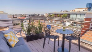 A rooftop terrace with a grey sofa, two chairs, a small table, and potted plants. - NH Madrid Lagasca (Madrid)