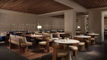Un restaurante moderno con muebles de madera, mesas redondas y un techo con vigas de madera.