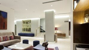 A modern hotel lobby with a seating area, a staircase, and a reception desk. - NH Madrid Lagasca (Madrid)