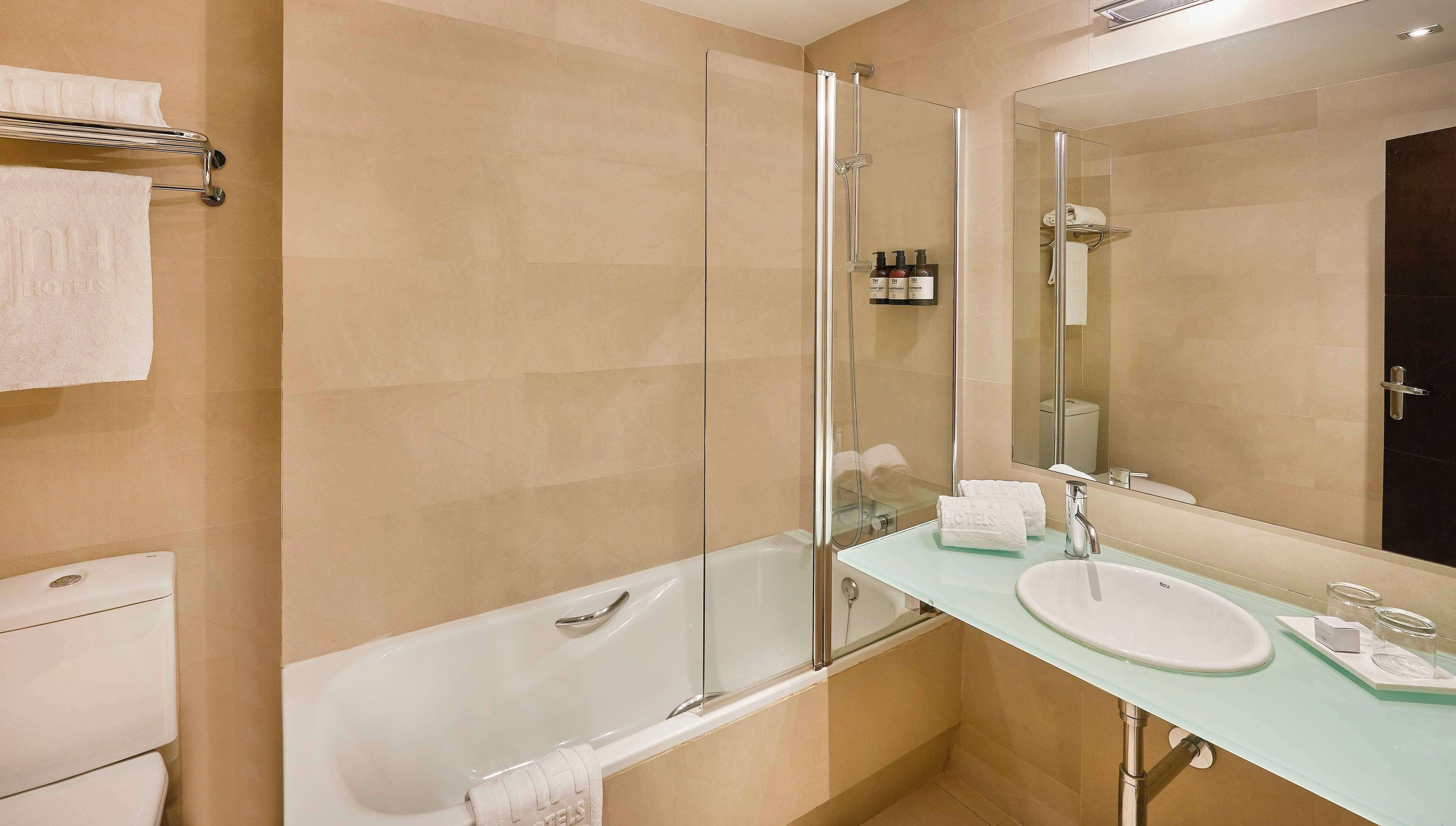 Ein modernes Badezimmer mit einer gläsernen Duschkabine, einer weißen Badewanne und einem Waschbecken mit Glasplatte.
