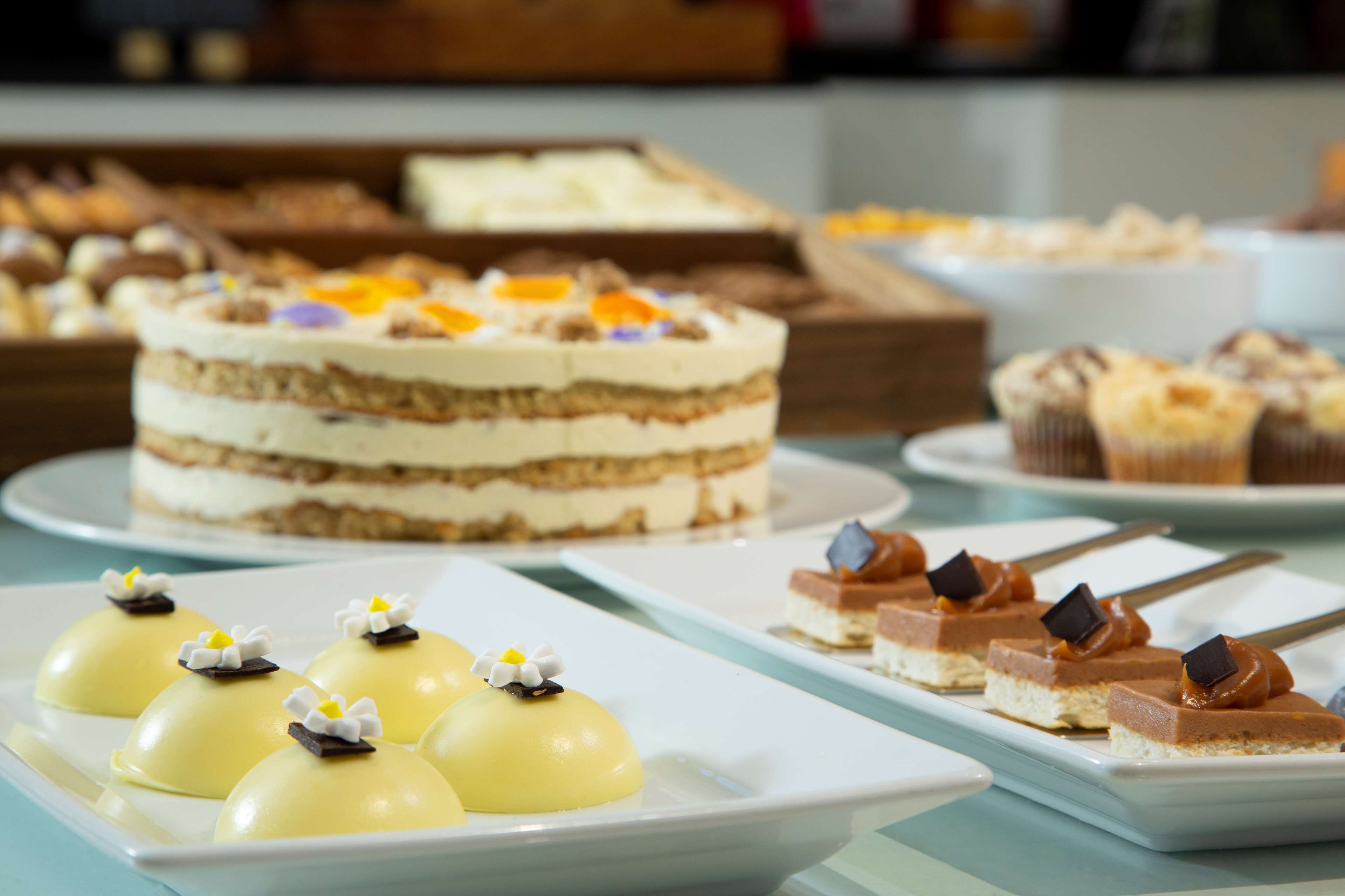 A variety of desserts on display, including a layered cake, cupcakes, and other sweet treats.