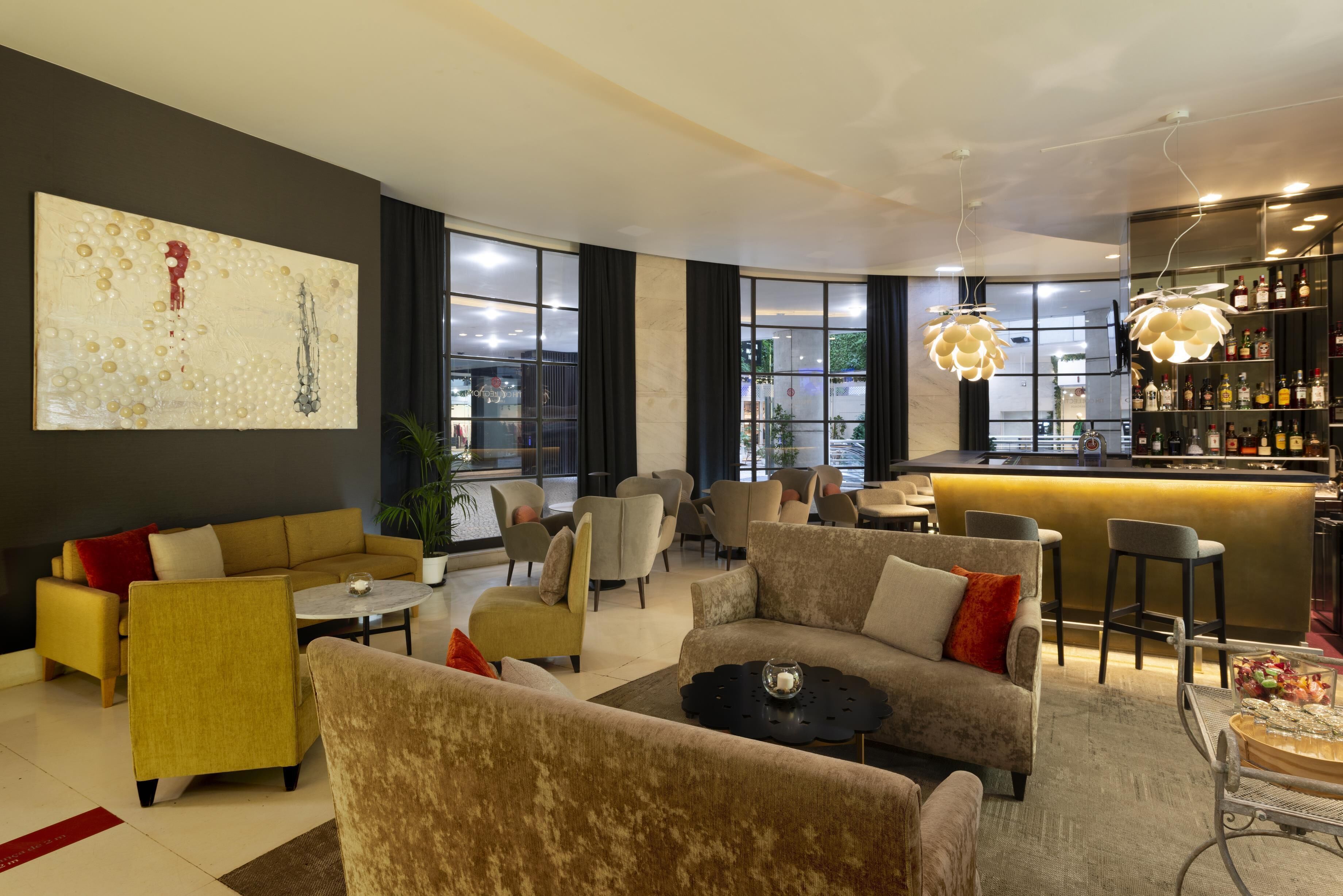 Un'area lounge moderna con divani, poltrone e un bancone bar.