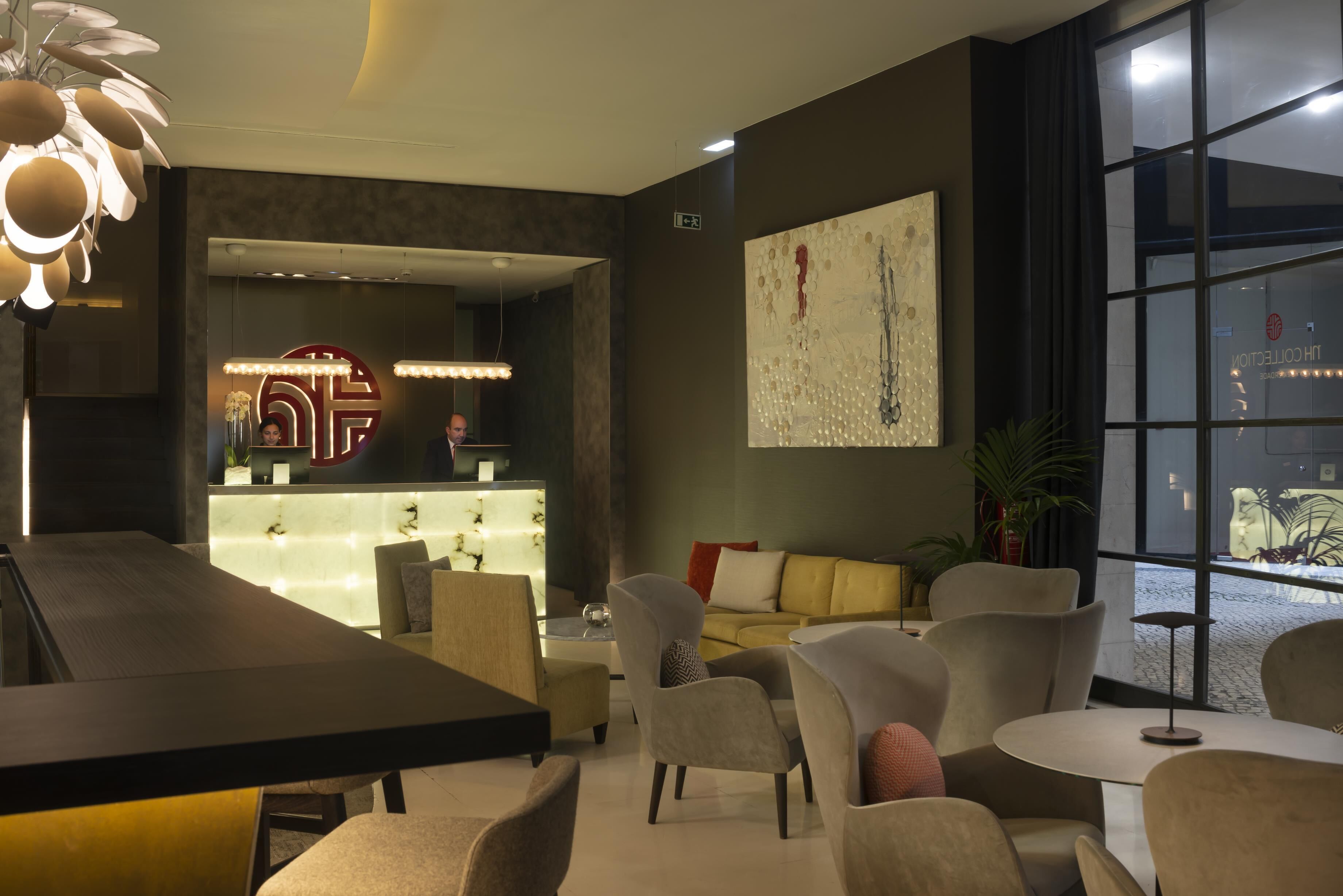 Un moderno vestíbulo de hotel con una recepción, zona de estar y ventanas amplias.