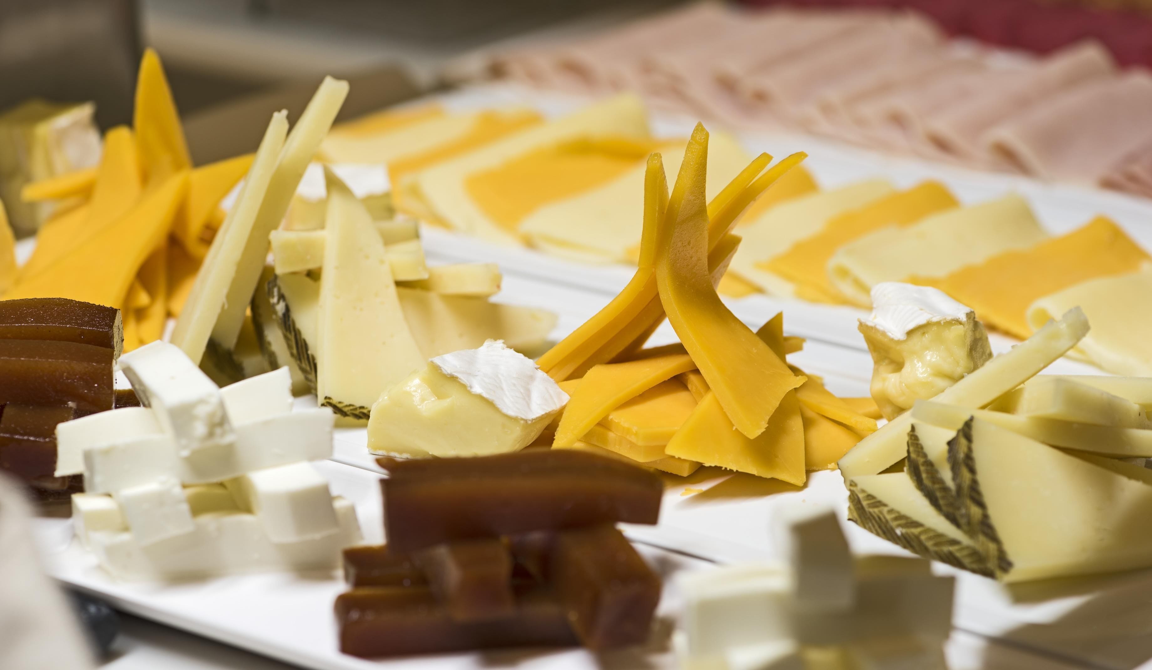 A variety of cheeses and cured meats on a white plate.