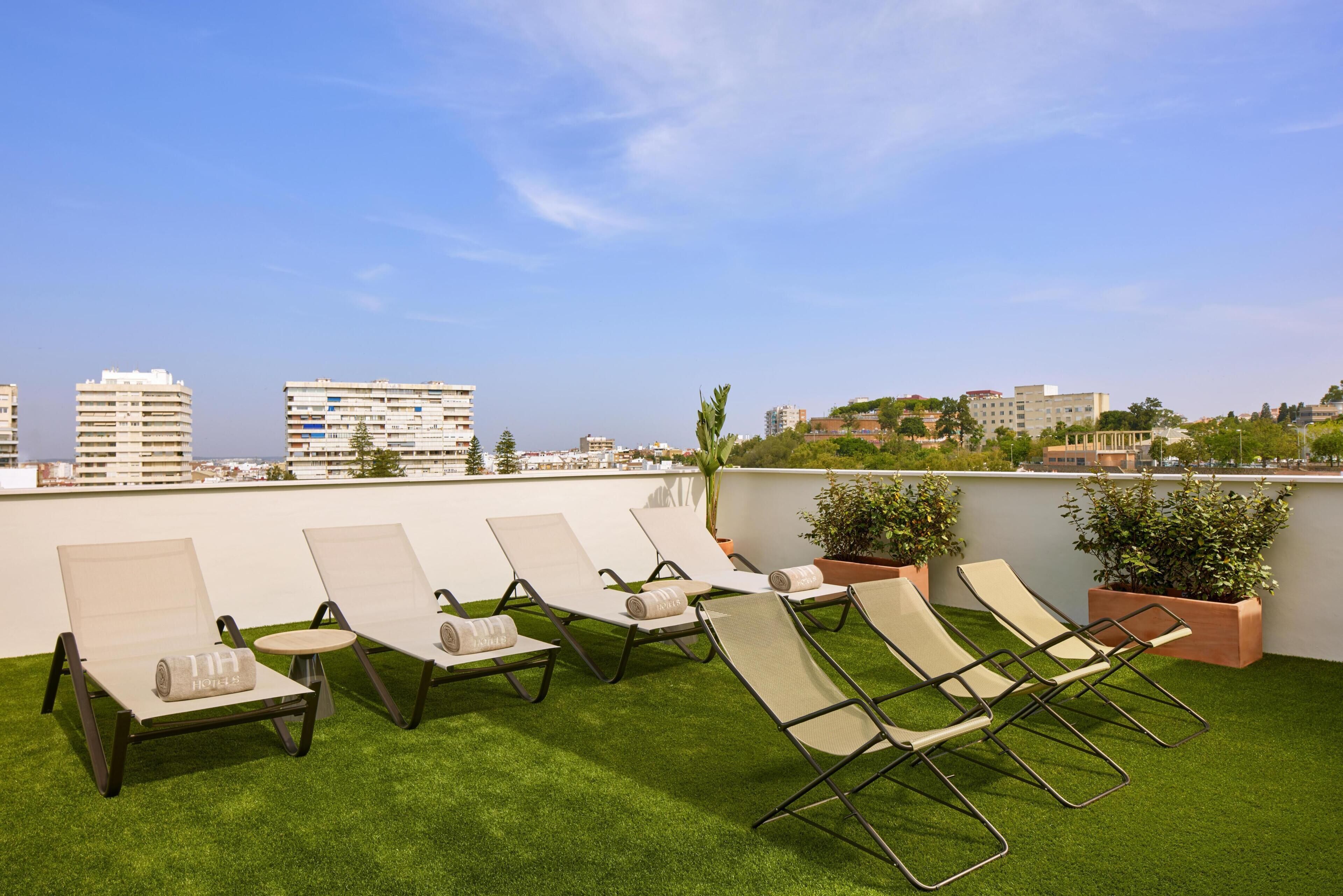 Terraço no telhado com espreguiçadeiras e vista para a paisagem urbana.