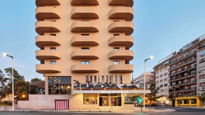 A modern hotel with a unique architectural design featuring multiple balconies and a prominent entrance. - NH Luz Huelva (Huelva)