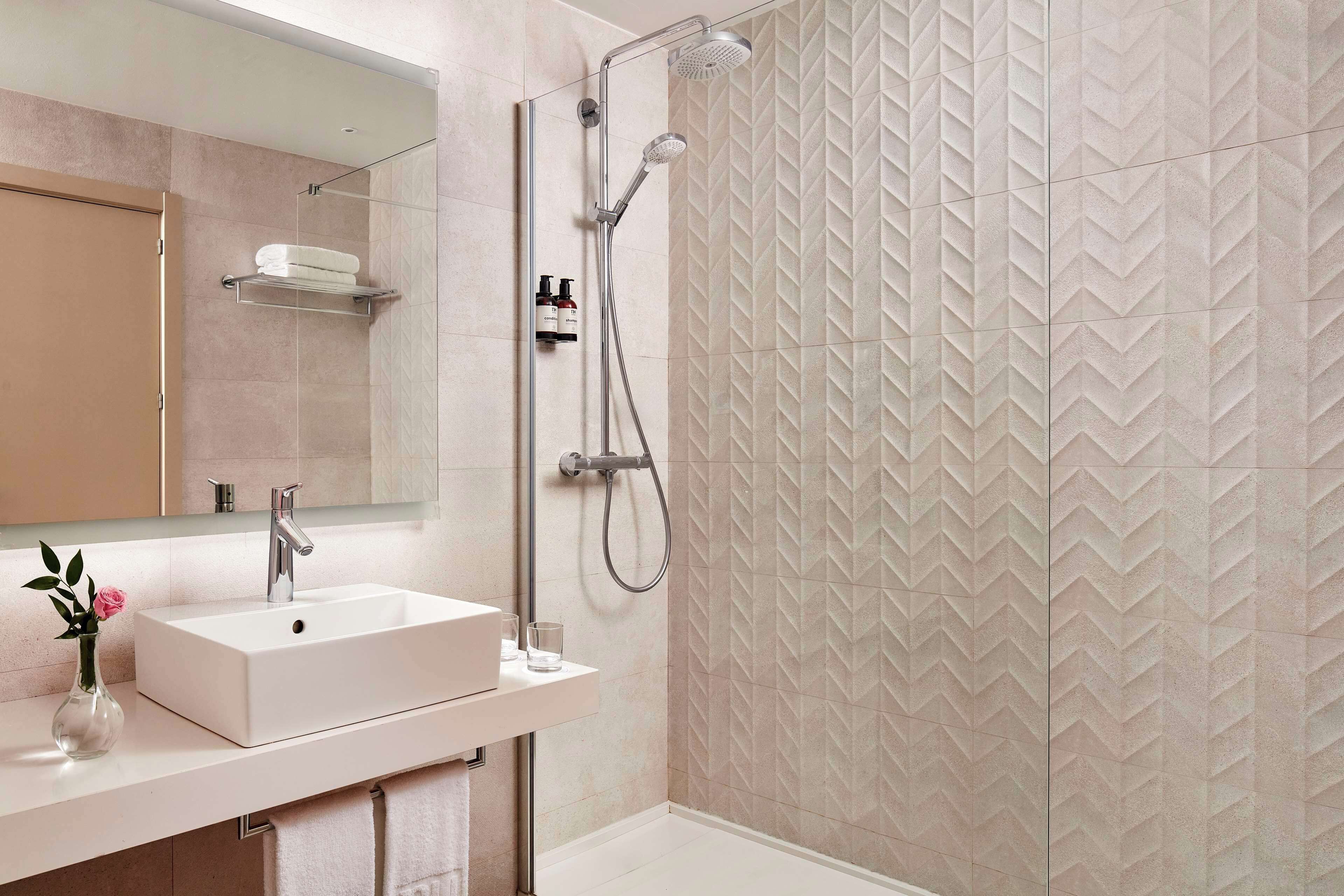 A modern bathroom with a rectangular sink, a handheld showerhead, and a wall-mounted towel rack.