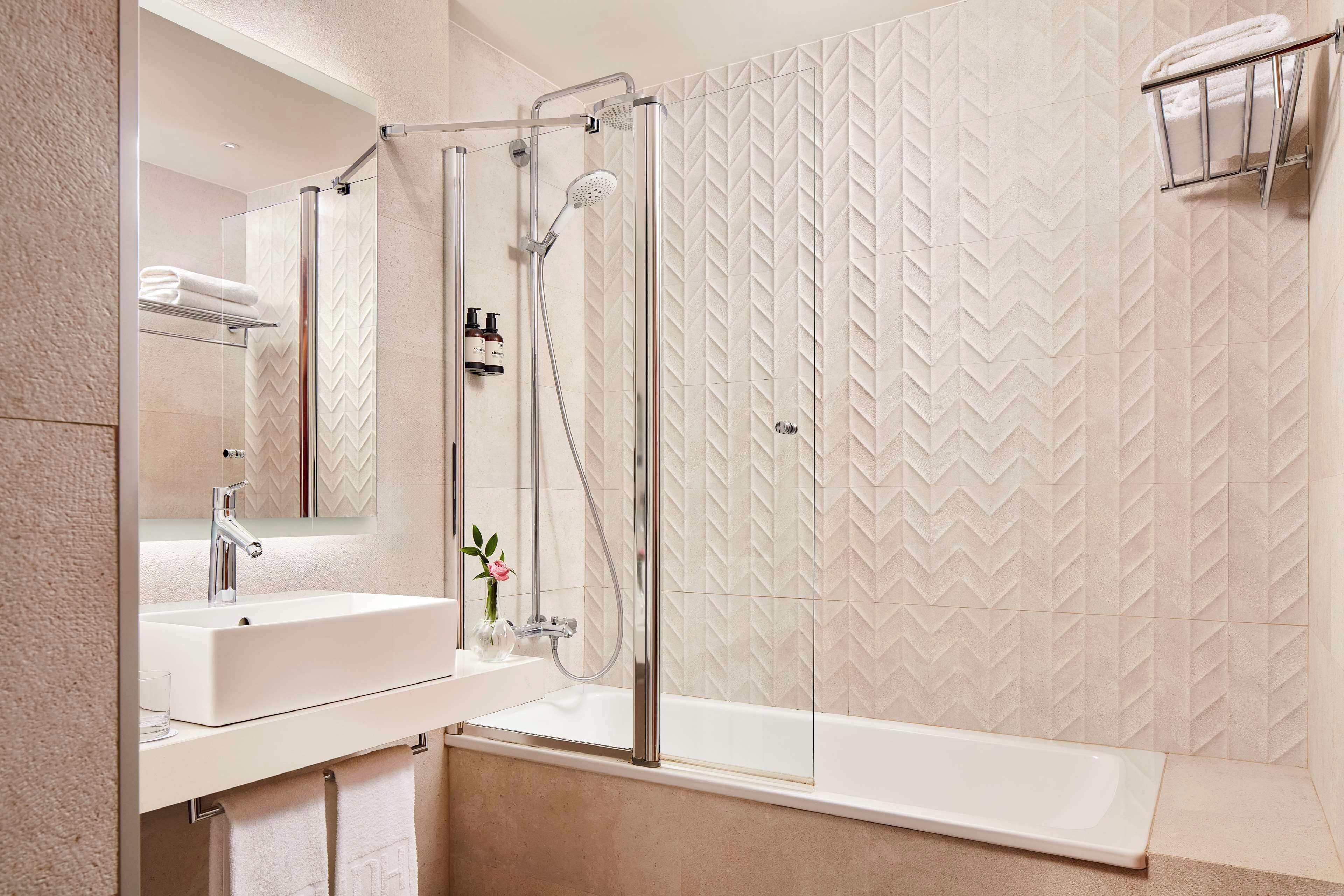A modern bathroom with a glass-enclosed shower, a white sink, and a large bathtub.