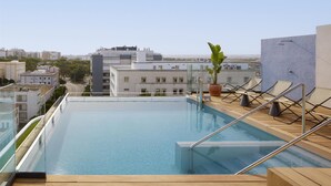 A rooftop infinity pool with a clear view of the cityscape in the background. - NH Luz Huelva (Huelva)