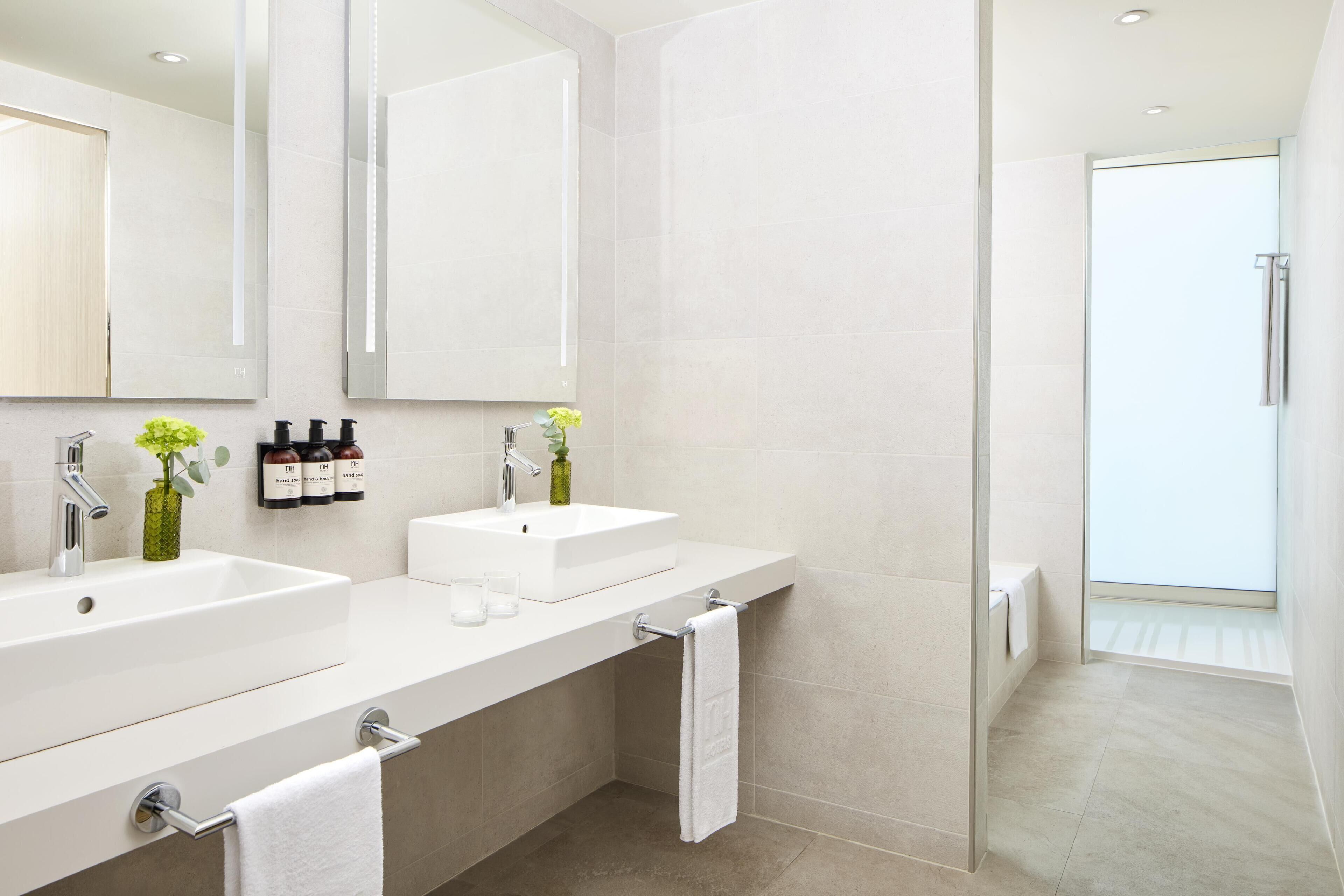 Un baño moderno con dos lavamanos, un espejo grande y cabina de ducha de vidrio.