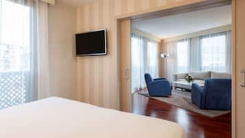 Habitación de hotel con una cama grande, un televisor de pantalla plana en la pared, un sofá y una silla.