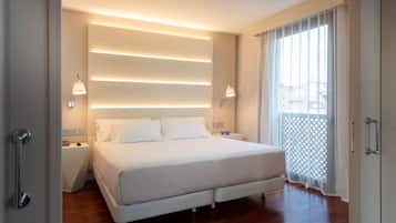Un dormitorio moderno con una cama grande, lámparas de noche y vistas a través de una ventana con cortinas translúcidas.