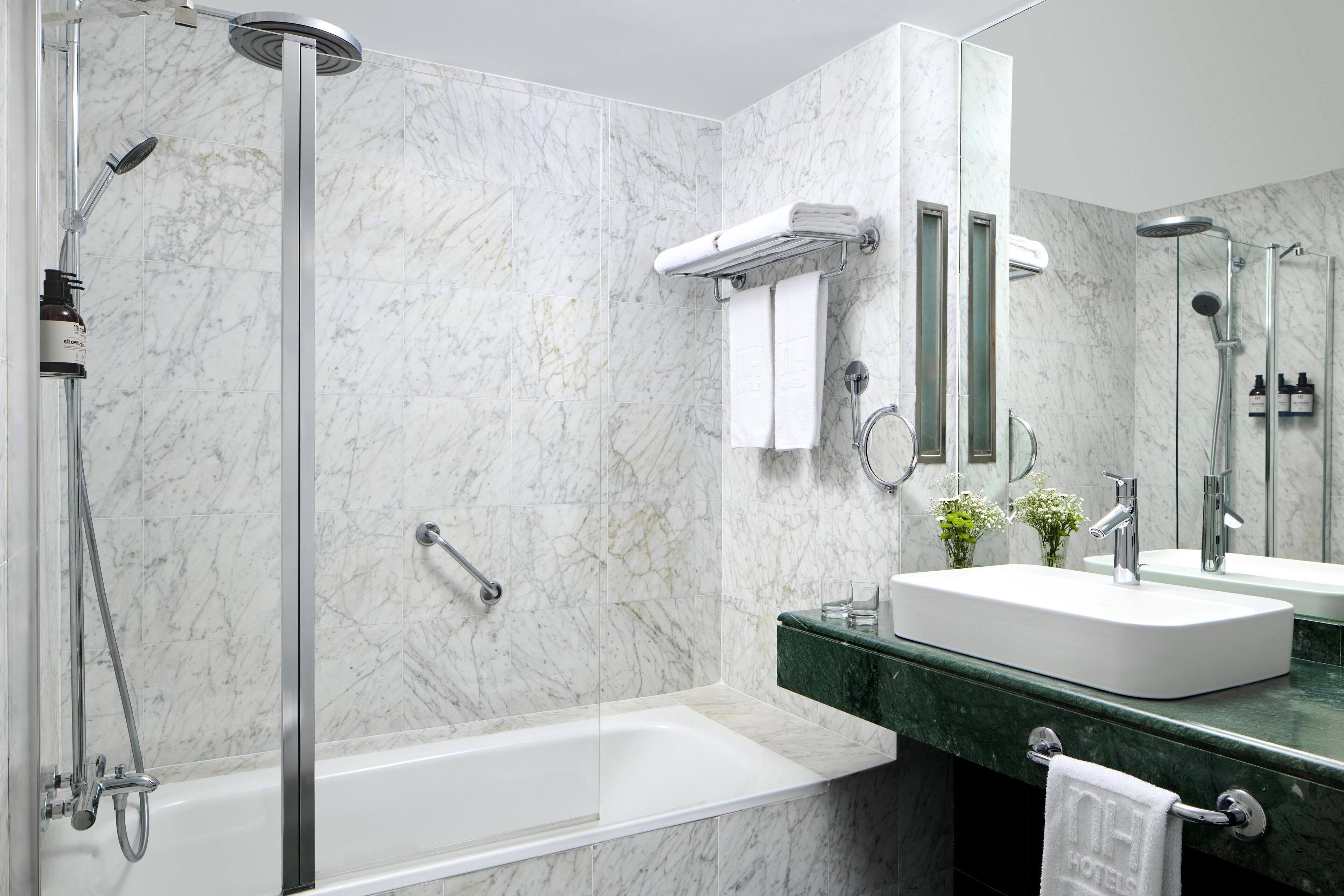 Un bagno moderno con doccia vetro, vasca e mobile lavabo con lavandino e specchio.