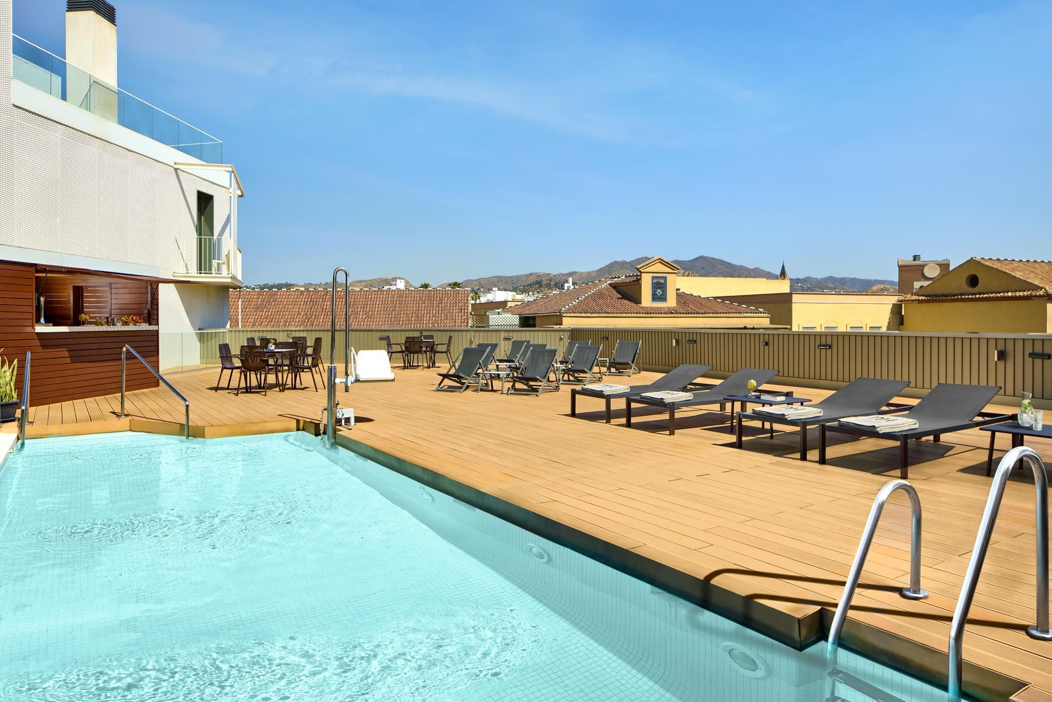 A rooftop pool area with lounge chairs and a bar.