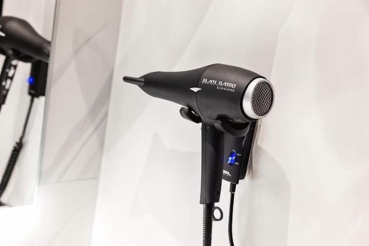 A hair dryer with a cord, mounted on a wall.