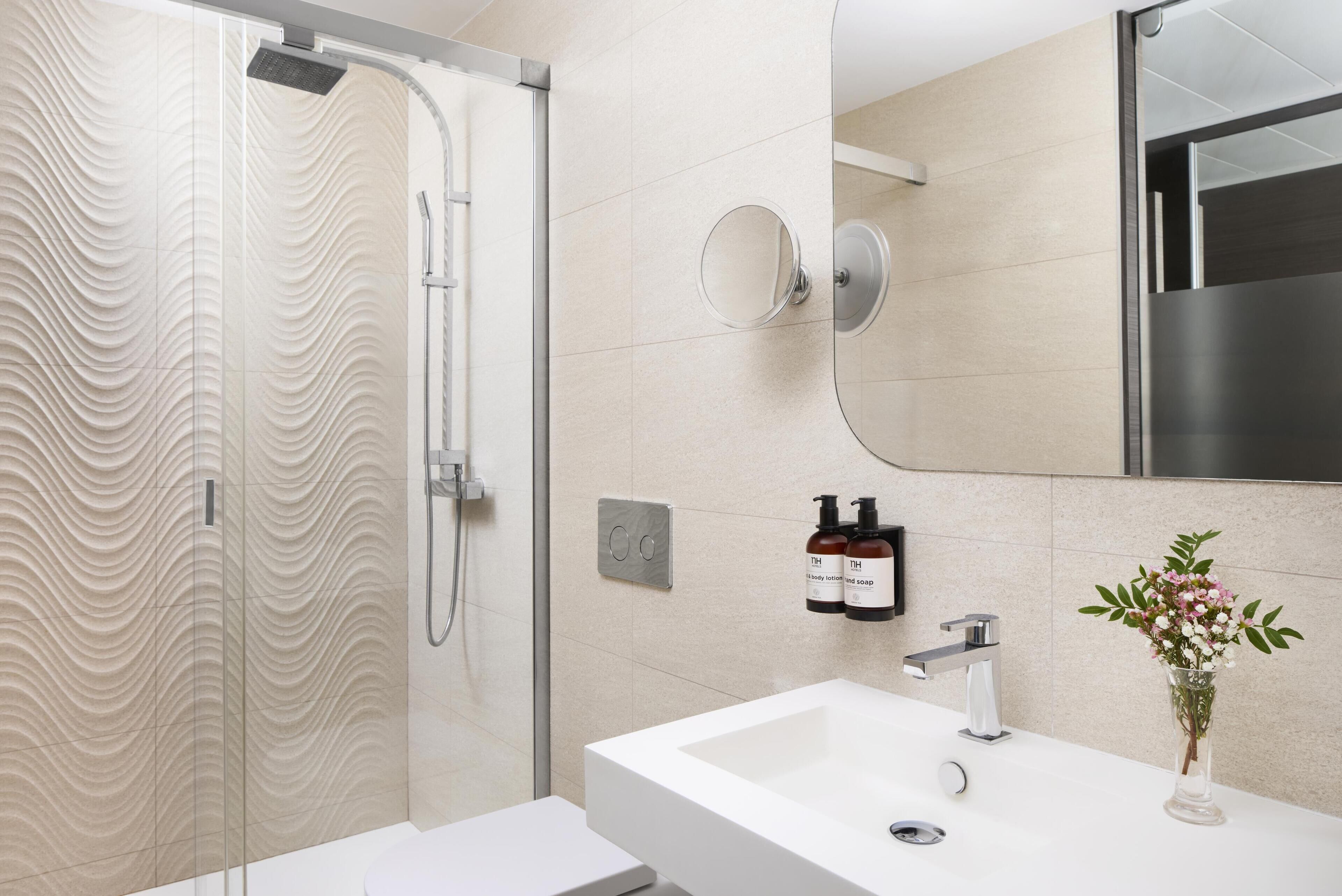A modern bathroom with a glass shower enclosure, a white sink, and a mirror.