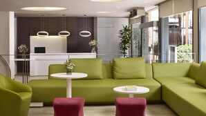 A modern living area with a green sofa, red ottomans, and a white coffee table.