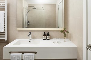 Un baño moderno con un espejo grande, un lavabo blanco y dos botellas de jabón de manos.