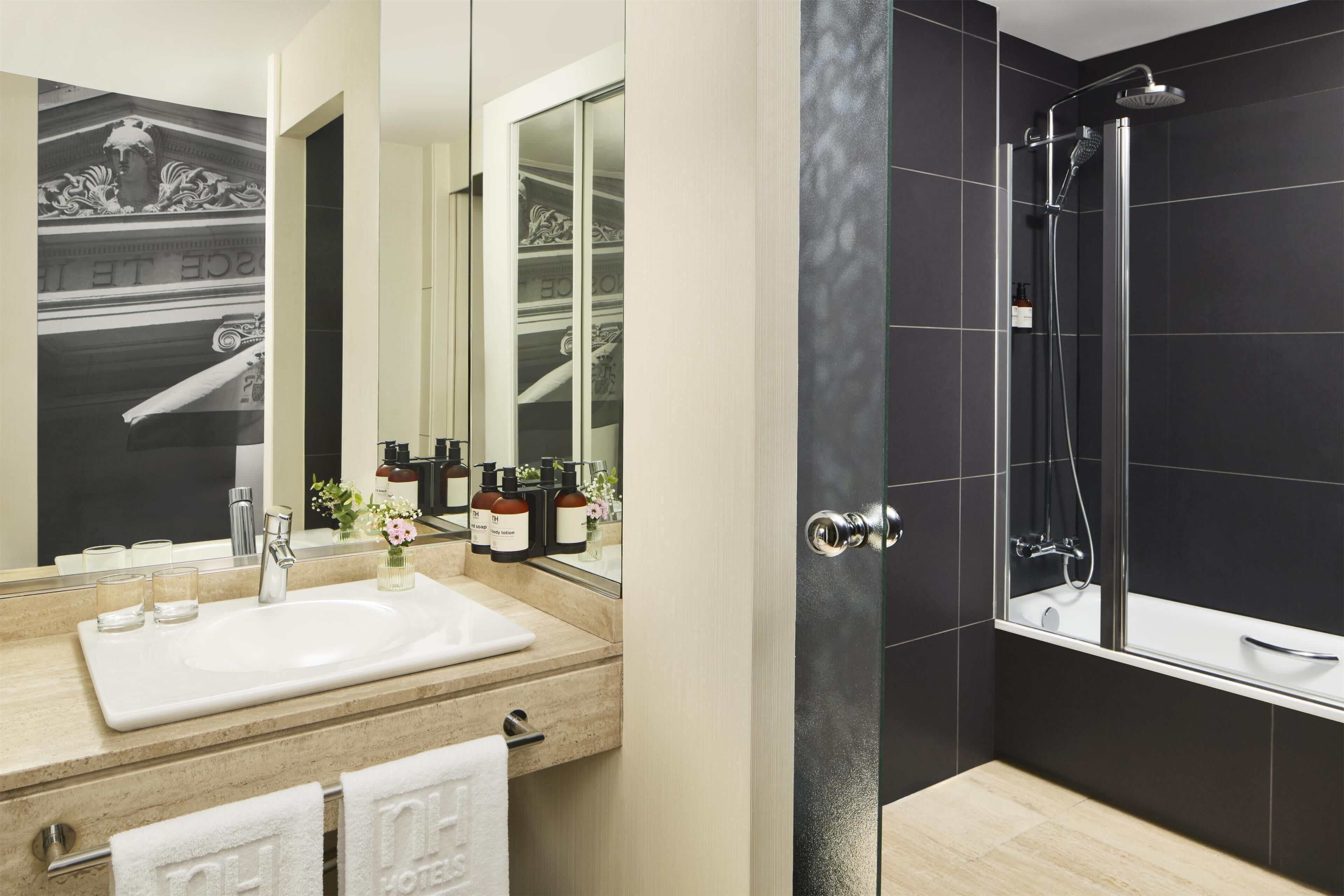 A modern bathroom with a white sink, a glass shower enclosure, and a large mirror.