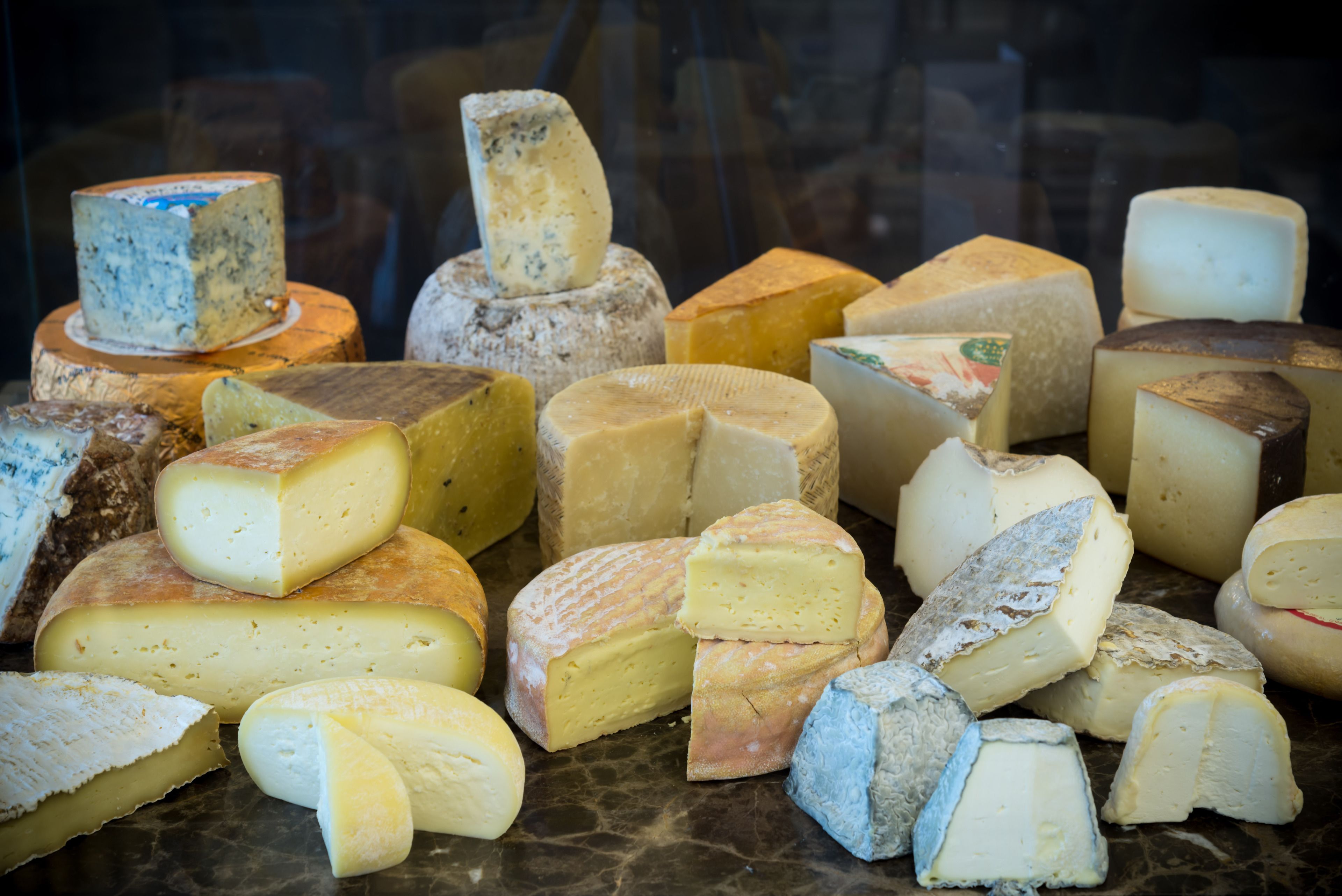 A variety of cheeses displayed in a glass case.