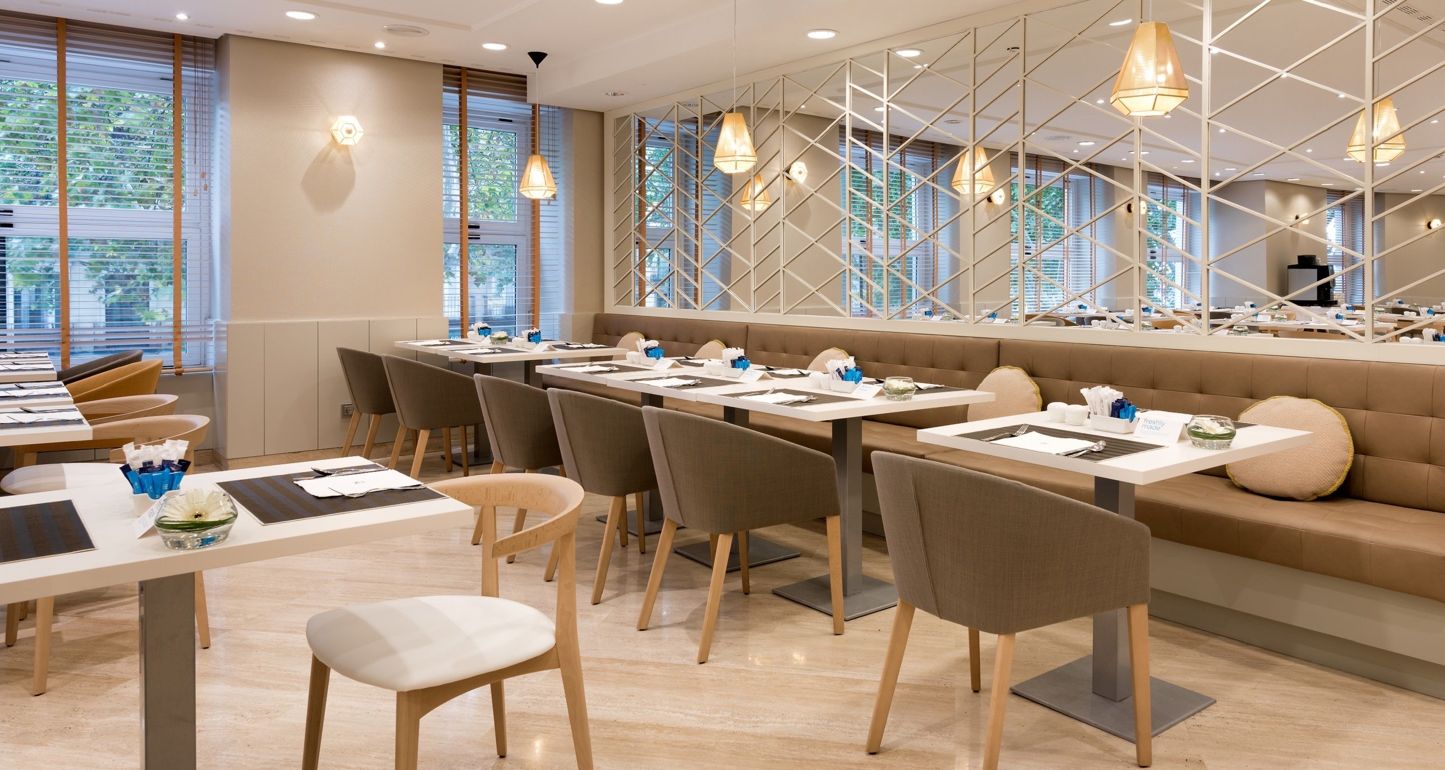 Un restaurante moderno con mesas largas, asientos acolchados e iluminación colgante.