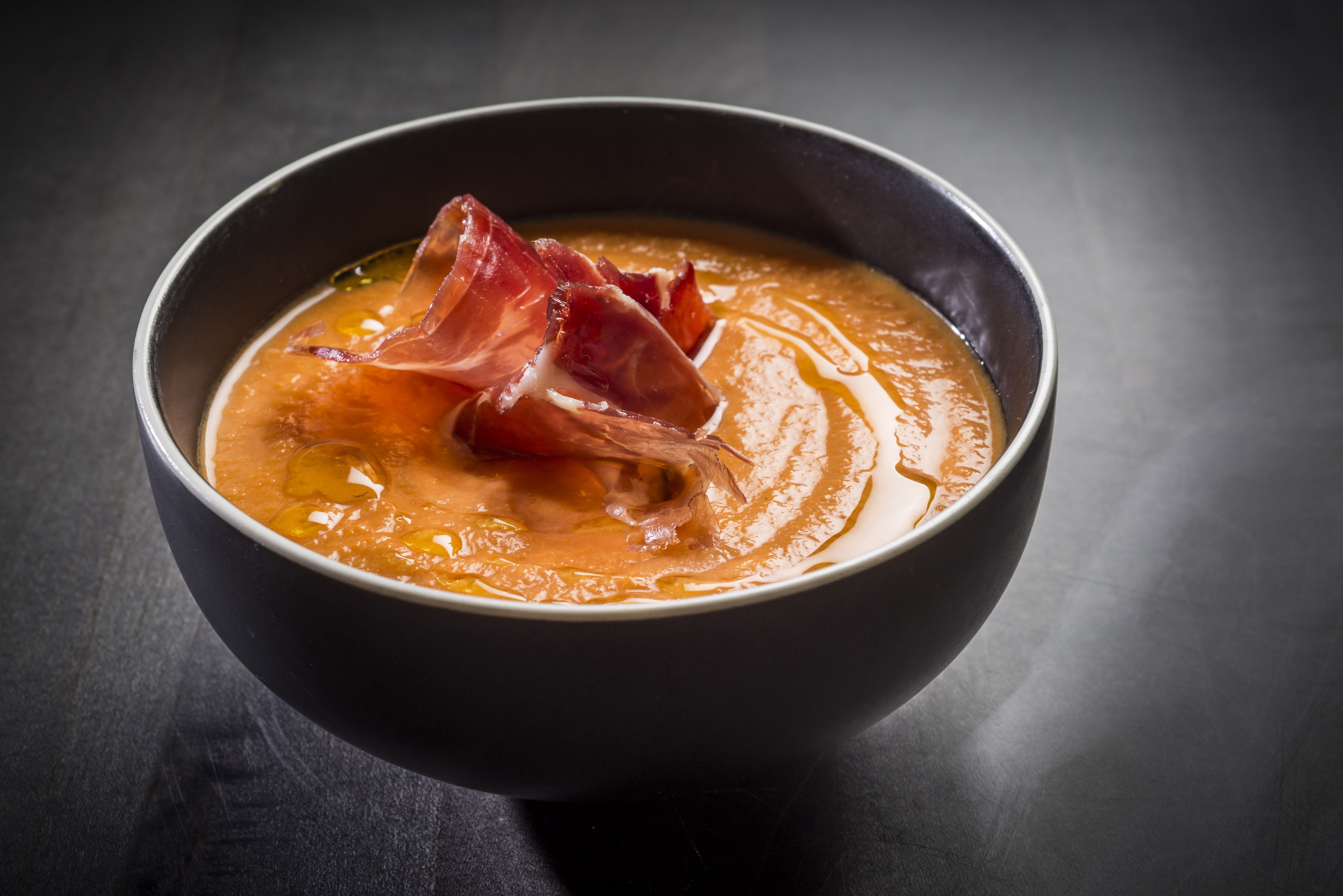 En skål soppa med en bit bacon ovanpå.