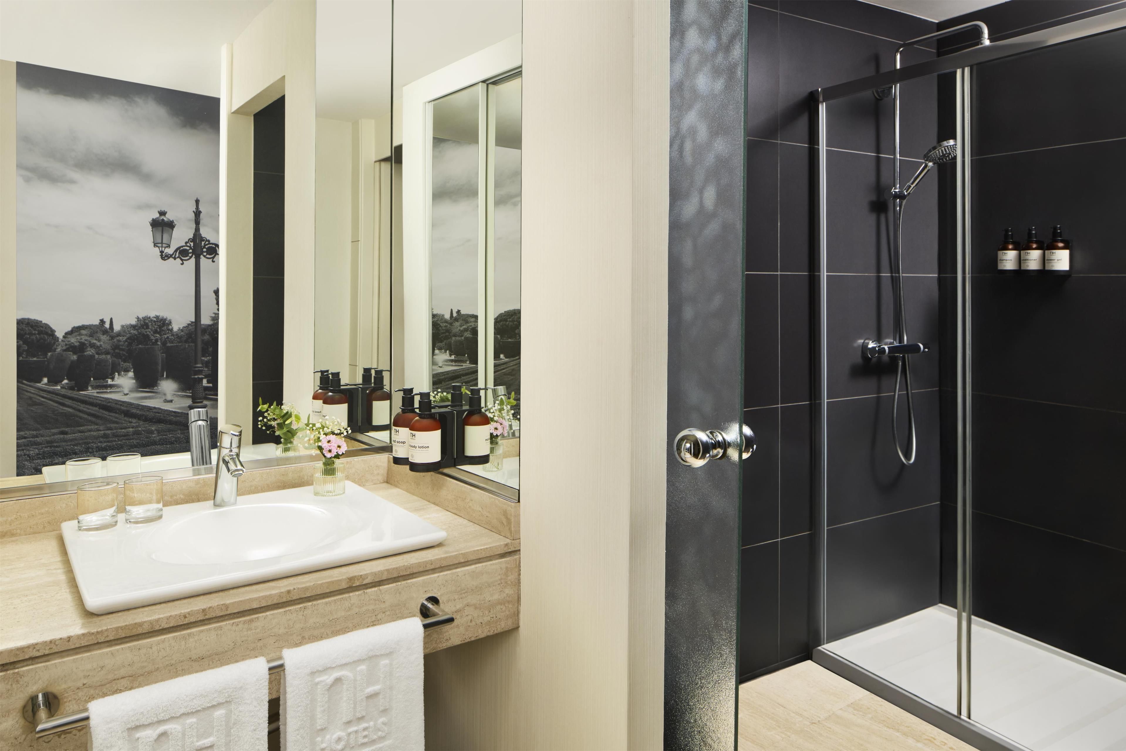 A modern bathroom with a large mirror, a sink, and a shower area.