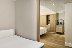 Un dormitorio moderno con una cama individual, un armario de madera y una pequeña zona de kitchenette.